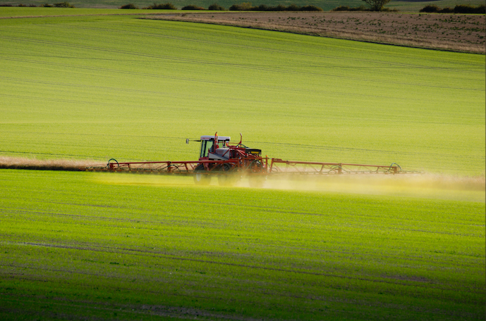 Image of a crop sprayer in a green agricultural field.