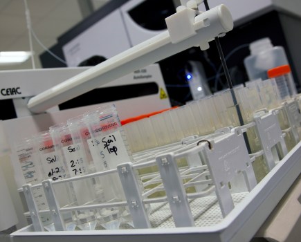 Image of a laboratory with rows of test tubes underneath a piece of scanning equipment.