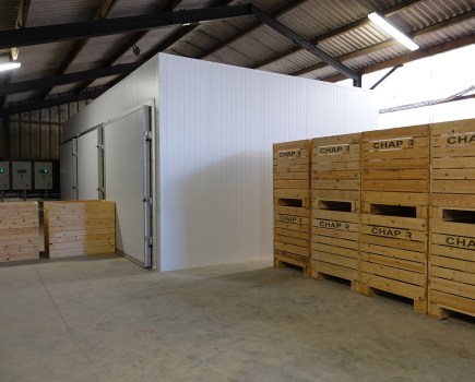 An image of a crop storage research unit, presenting as large wooden crated potato boxes, plus walk-in refridgerated units within a larger agricultural unit.