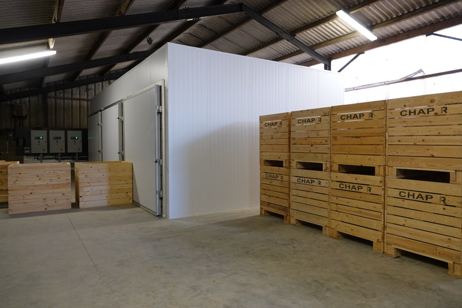 An image of a crop storage research unit, presenting as large wooden crated potato boxes, plus walk-in refridgerated units within a larger agricultural unit.